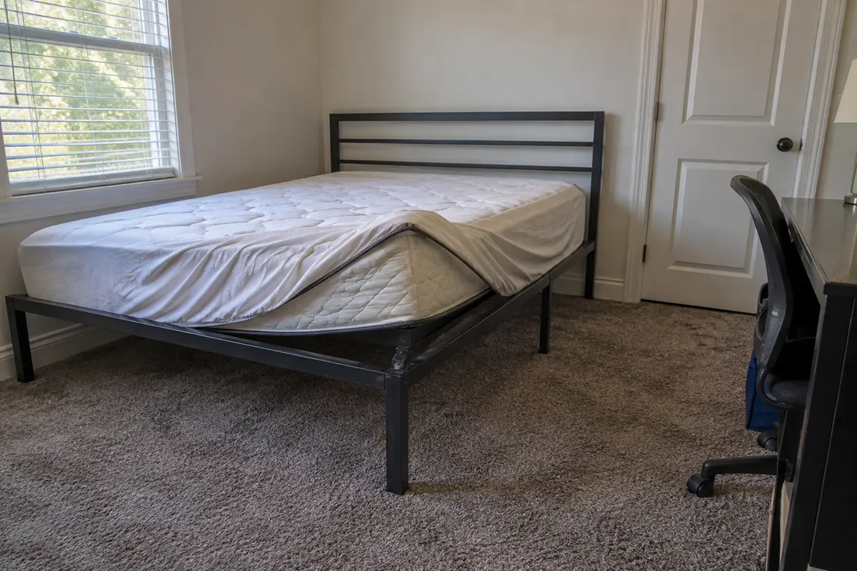 Bedroom with a metal bed frame, a mattress and an office chair, bed bug treatment in Folsom, CA