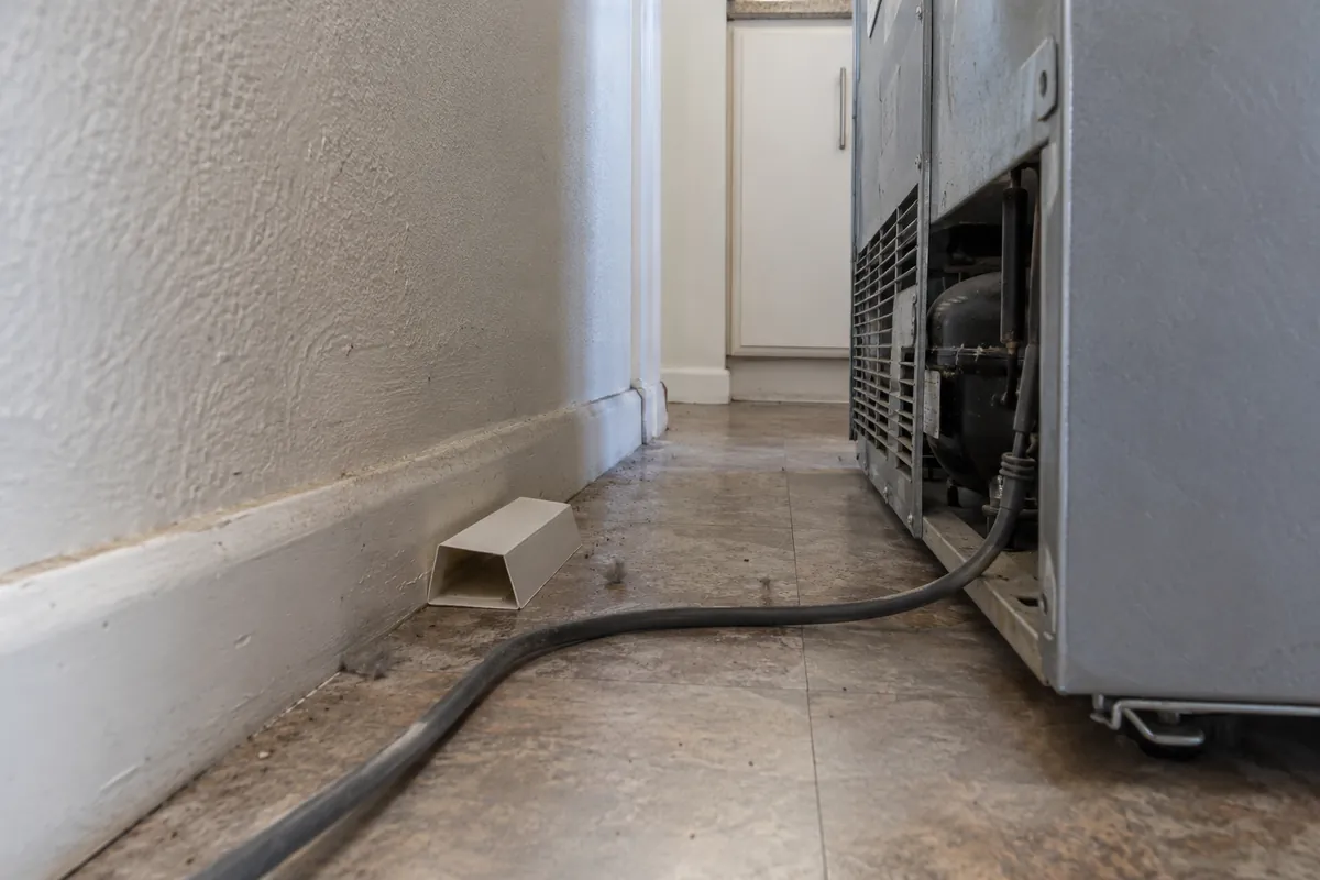 Pest monitor trap on the floor behind an appliance, cockroach control in Folsom, CA